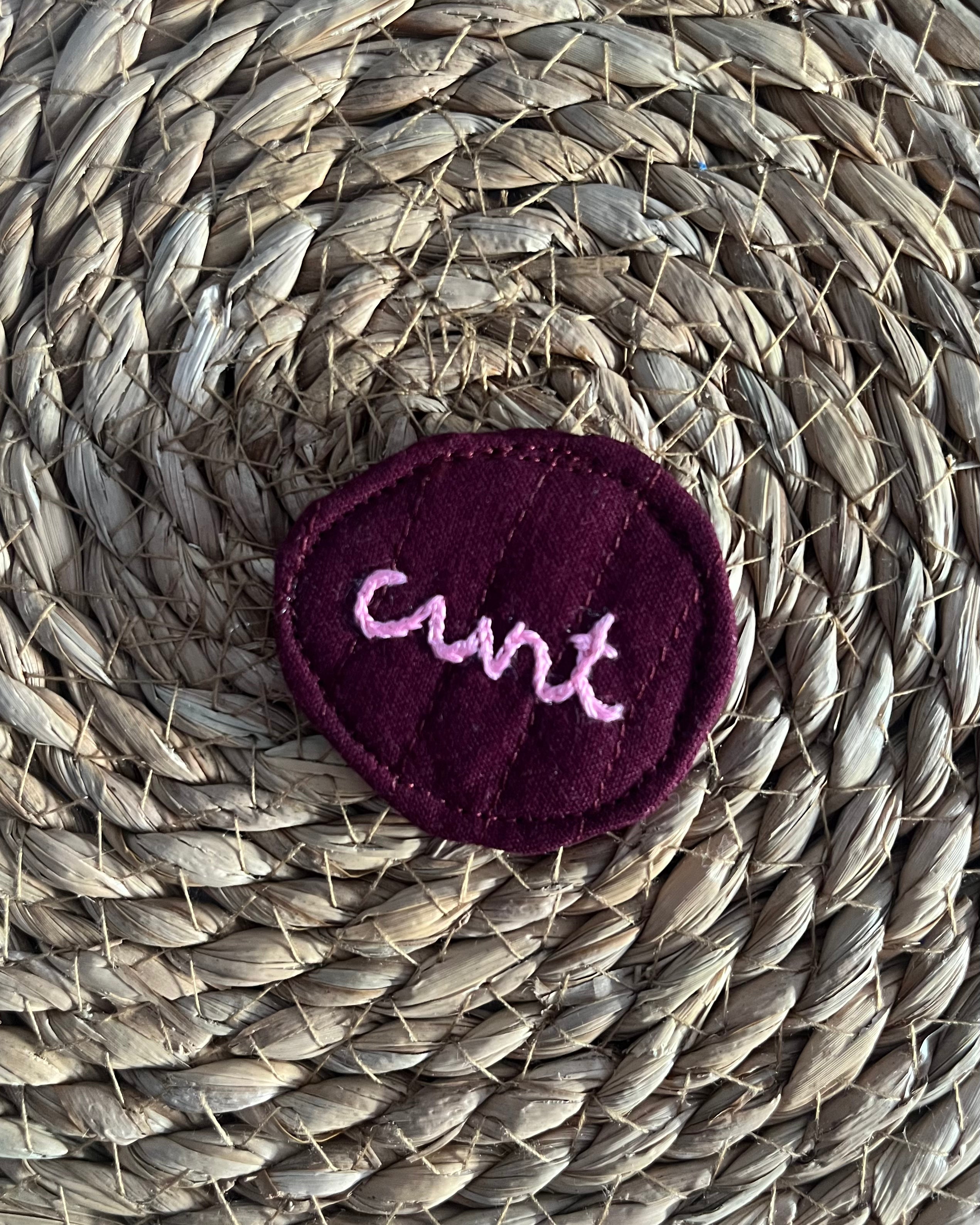Hand-embroidered "cunt" pin, quilted fabric offcut