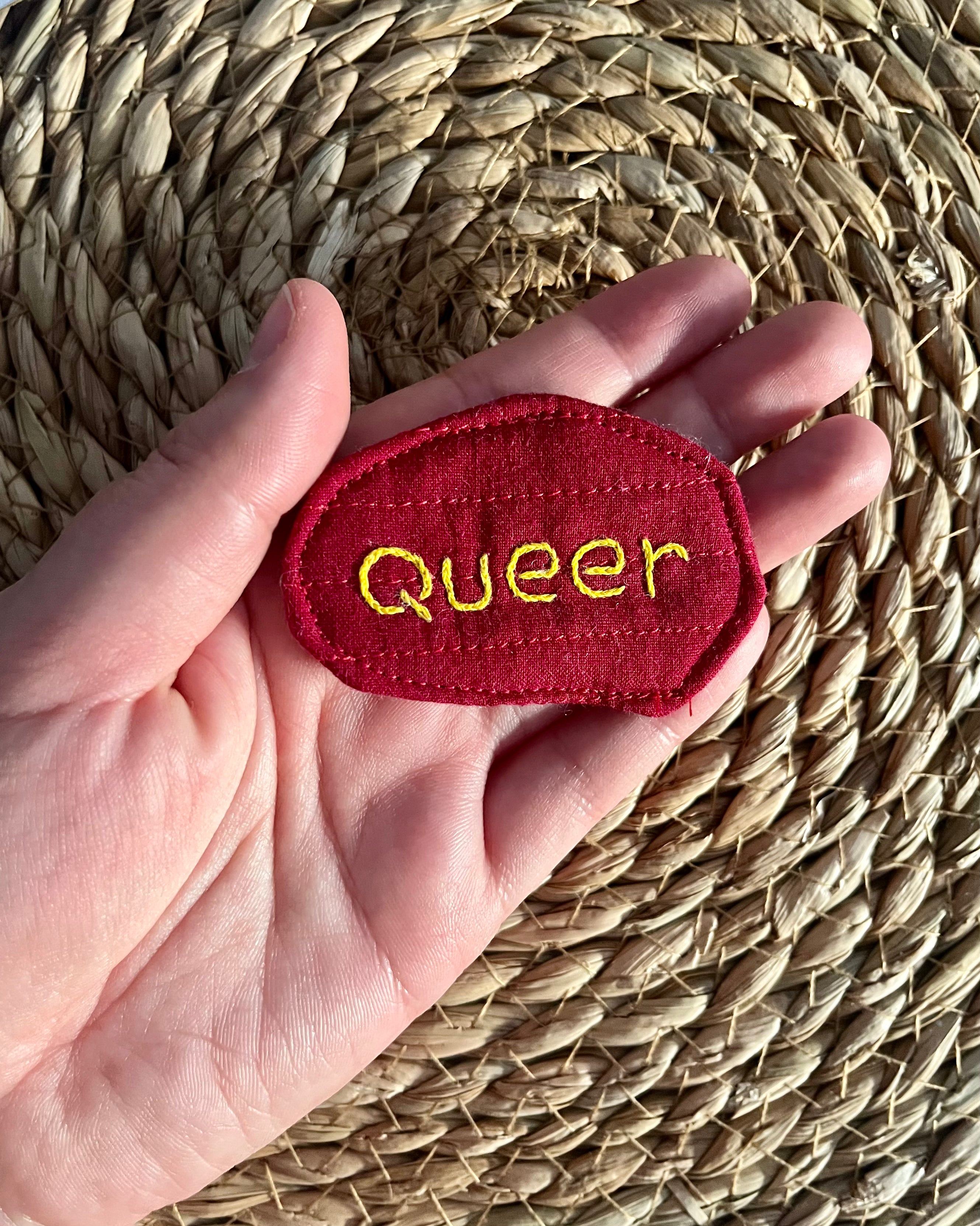 Hand-embroidered "queer" pin, quilted fabric offcut