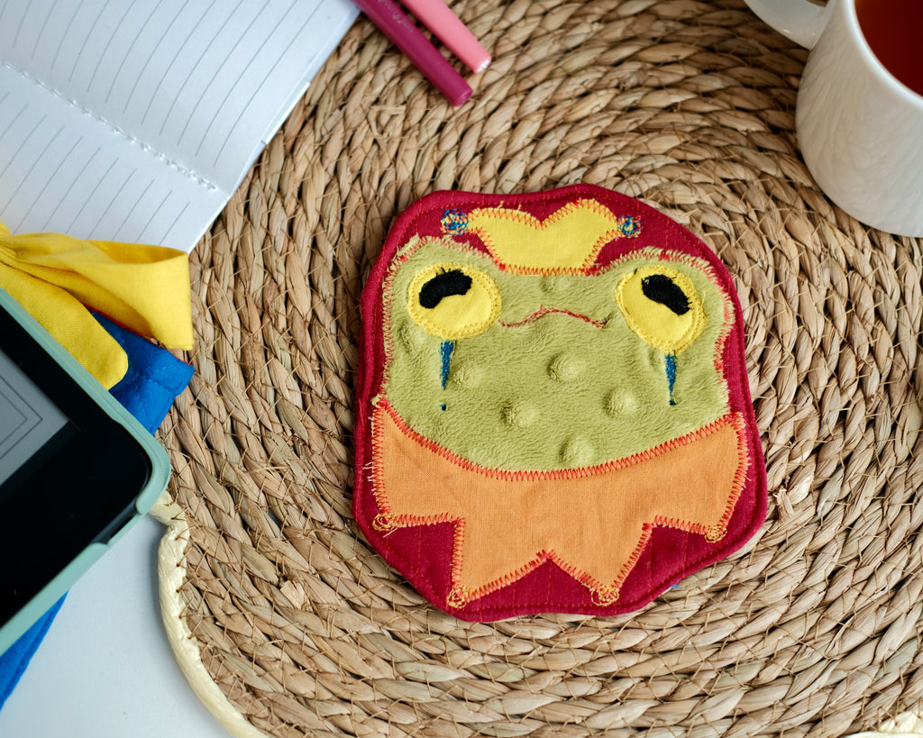 Sous-verre Clownimal Lucille la grenouille sur fond rouge foncé (chapeau jaune)