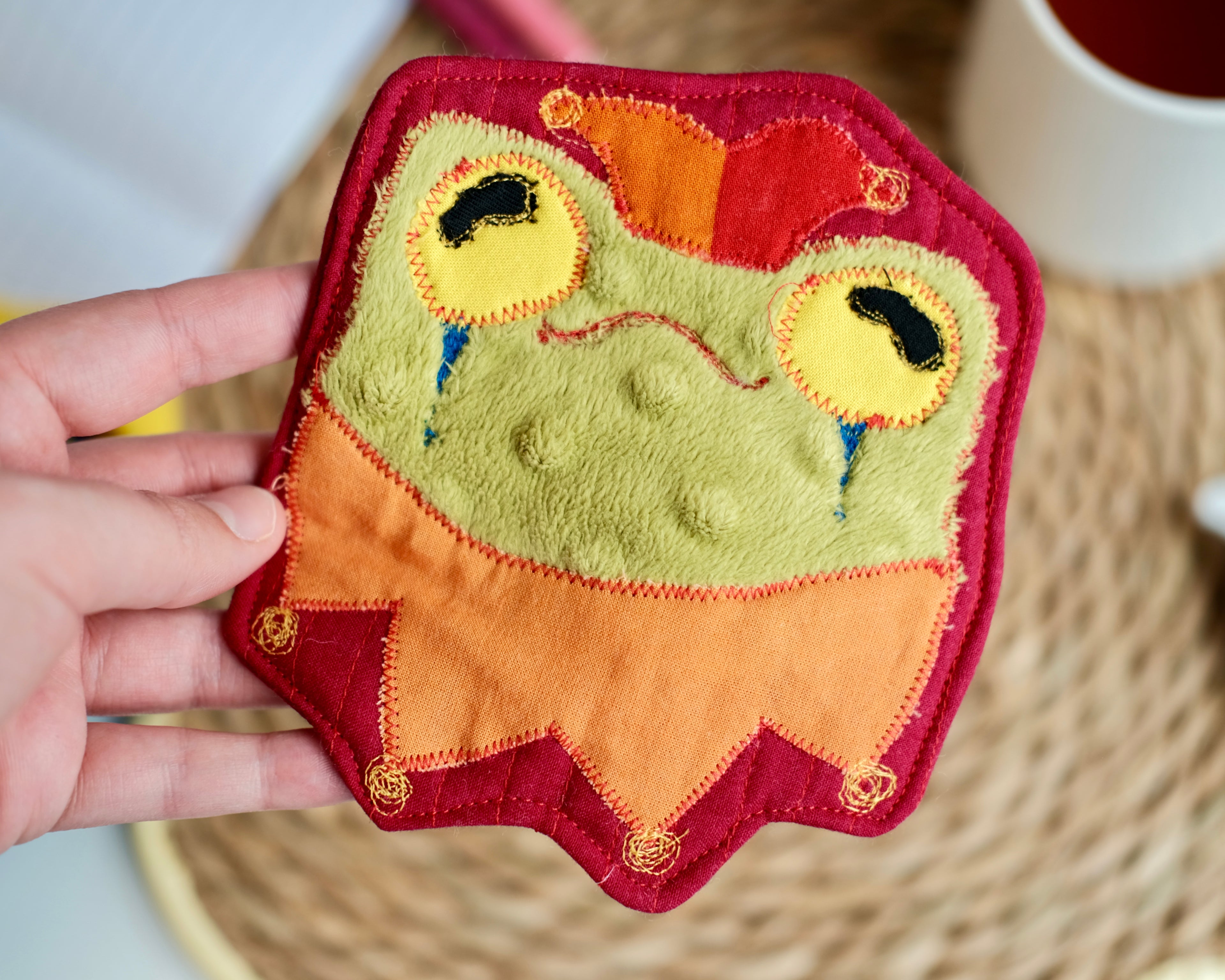 Sous-verre Clownimal Lucille la grenouille sur fond rouge foncé (chapeau orange-rouge)
